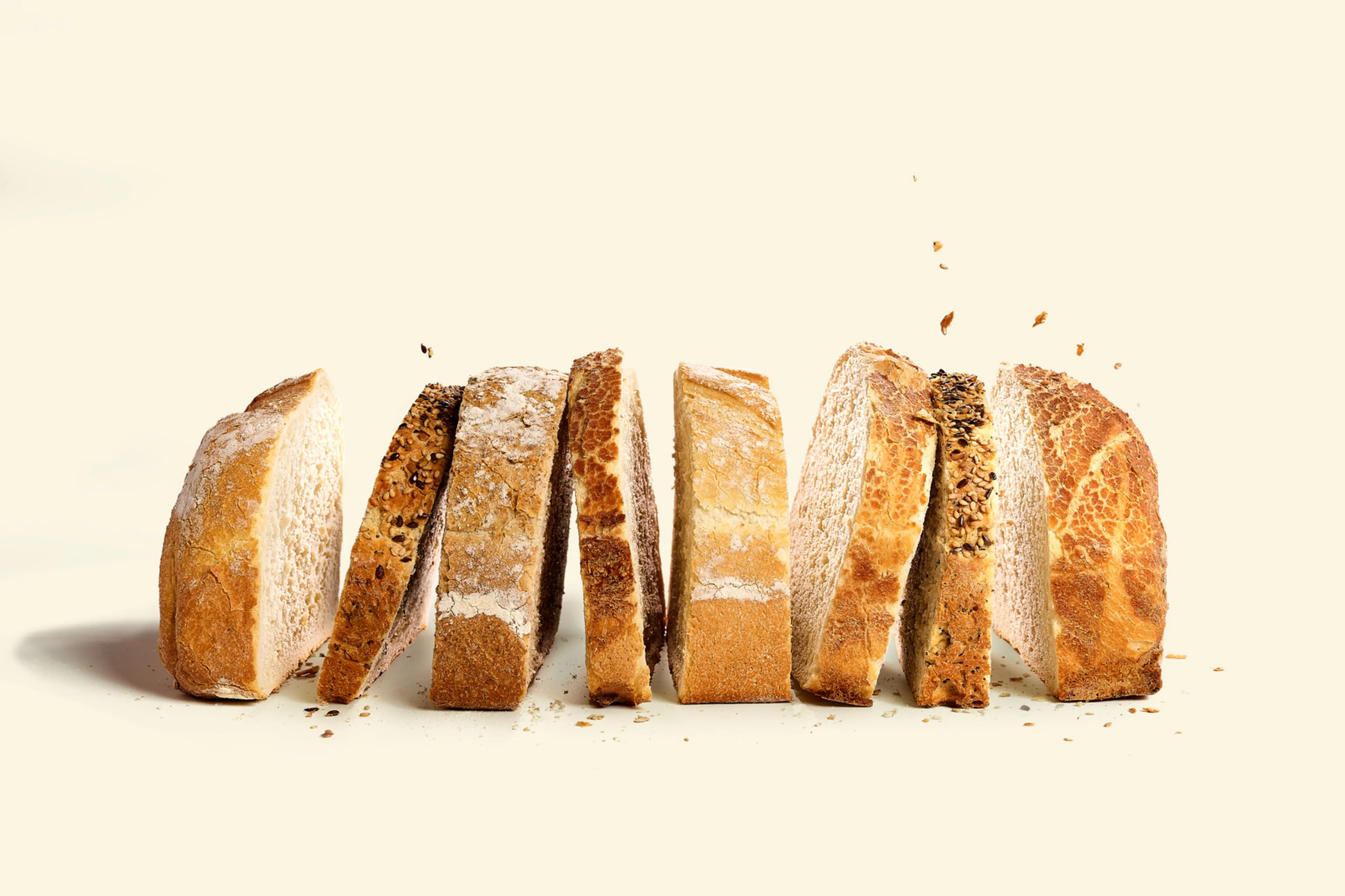 Gesneden Qubo-brood van Panos, rechtopstaand gepresenteerd tegen een lichte achtergrond. De sneden tonen verschillende korsten en zaden, met een ambachtelijke, rustieke uitstraling.