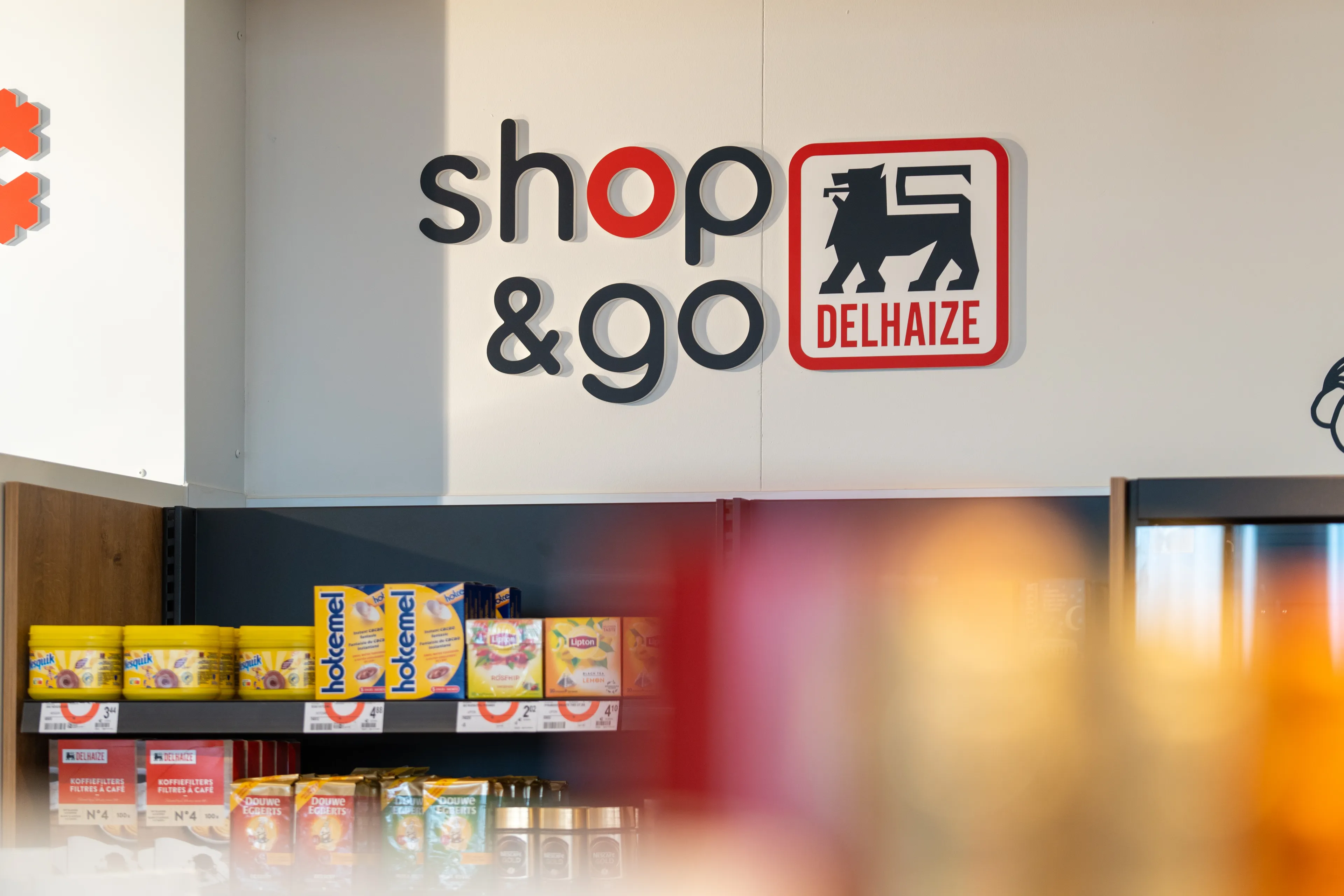 Binnenaanzicht van een Delhaize shop&go bij Q8, met zichtbaar Delhaize-logo op de muur.