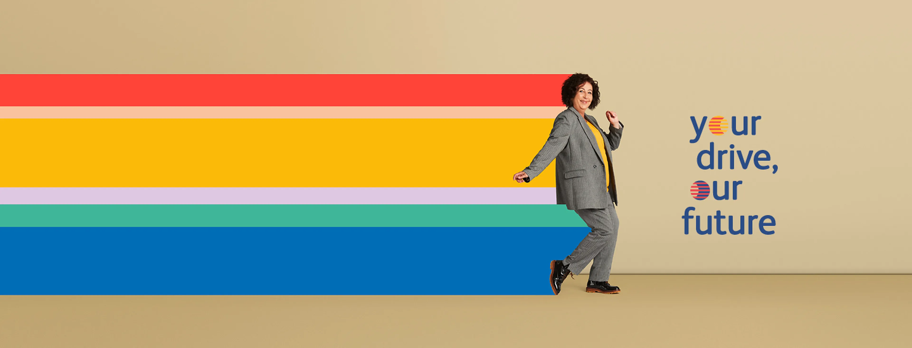 Femme aux cheveux noirs, en costume gris, posant joyeusement en tant que collaboratrice Q8.