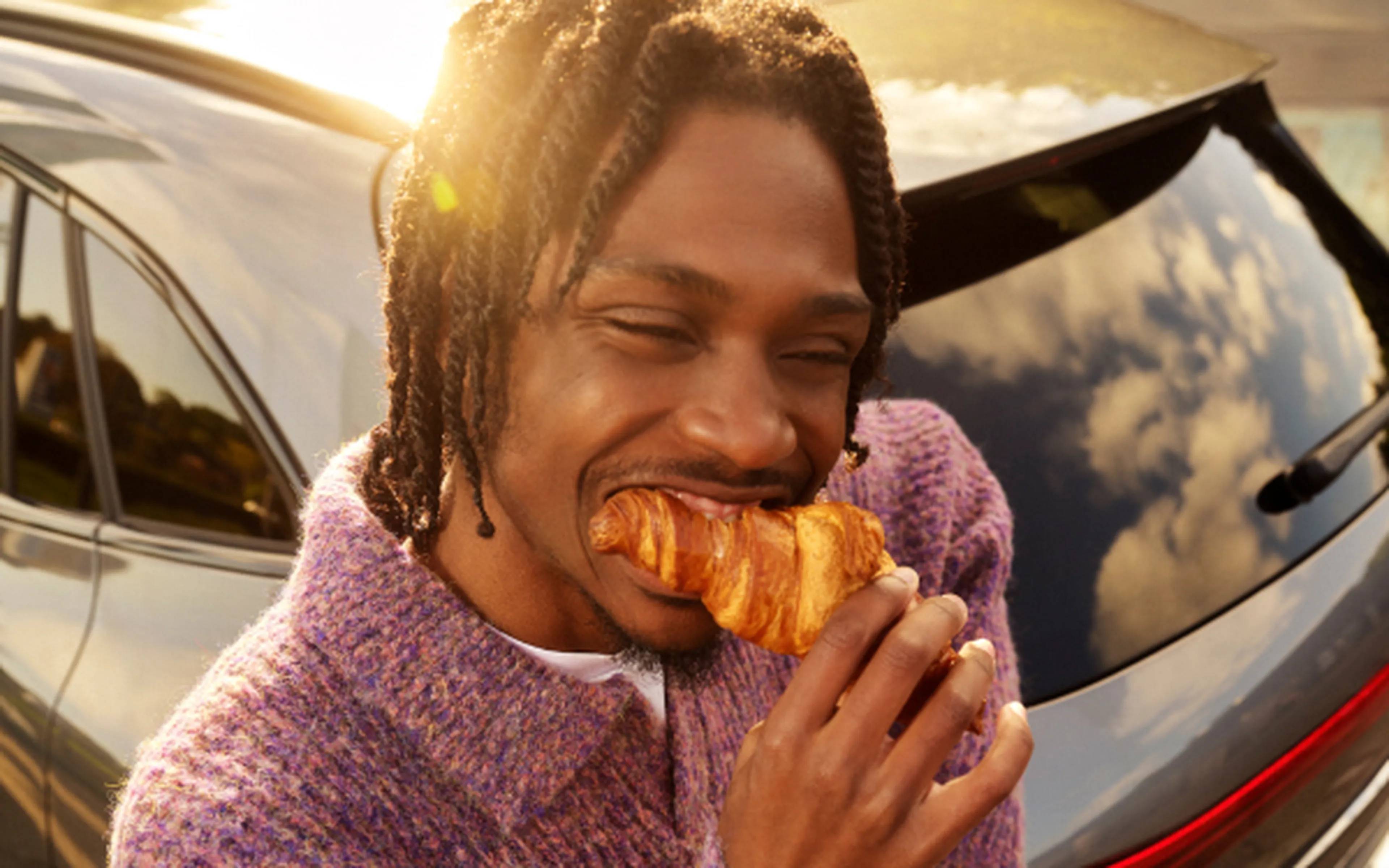 Man eet een croissant van Panos bij een Q8-station