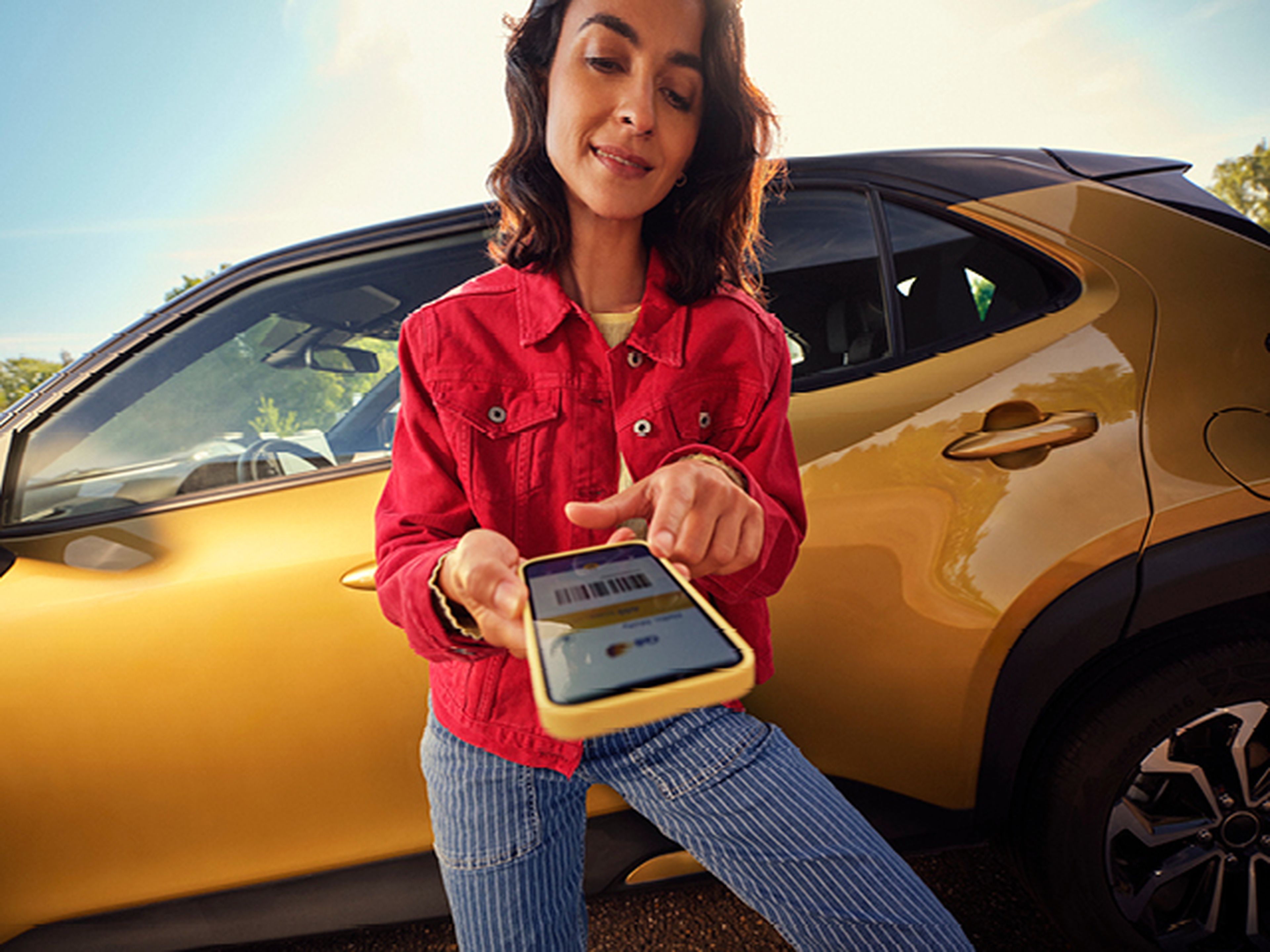 Femme pointe l'application Q8 sur son téléphone près d'une voiture jaune.