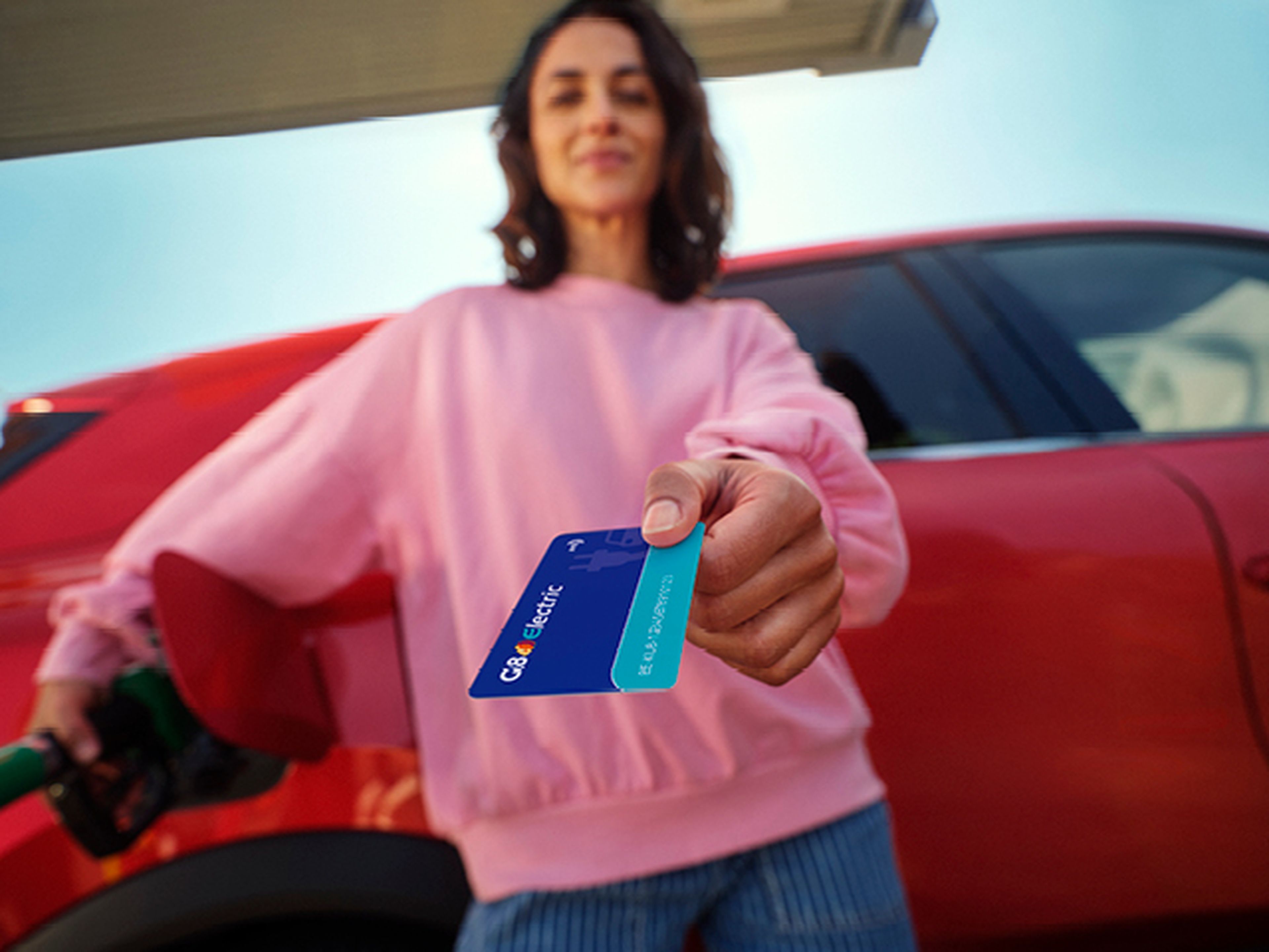 Woman showing a Q8 Liberty Card while refueling a red car.