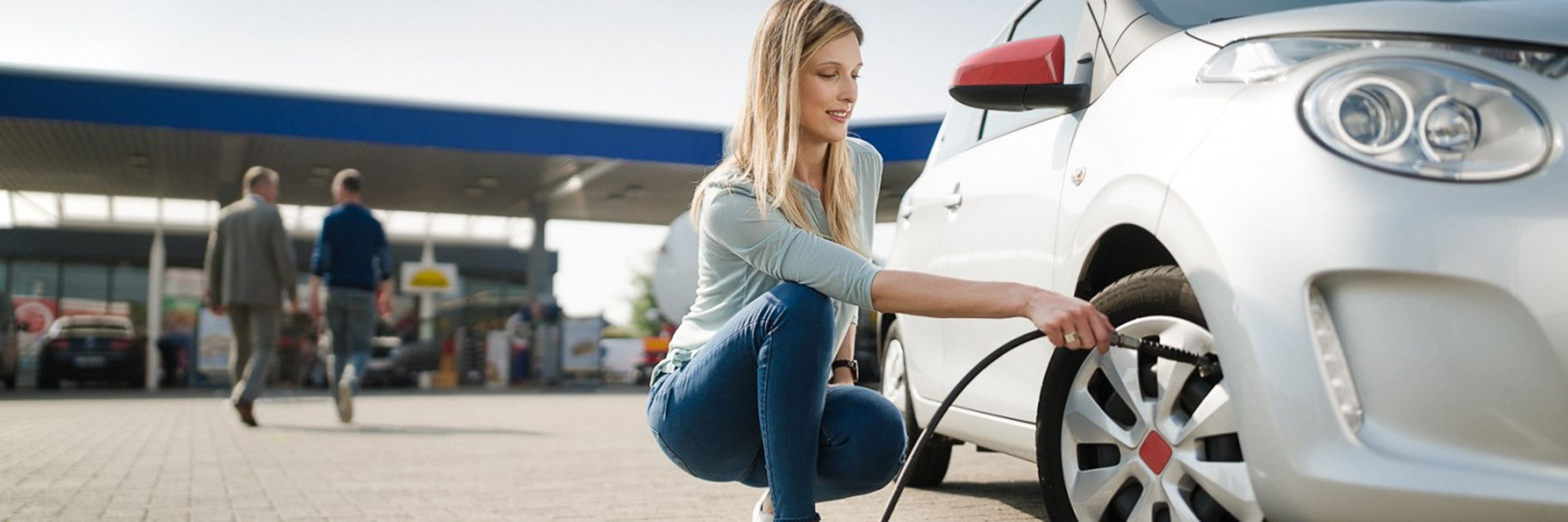 Vrouw die bij Q8 banden oppompt