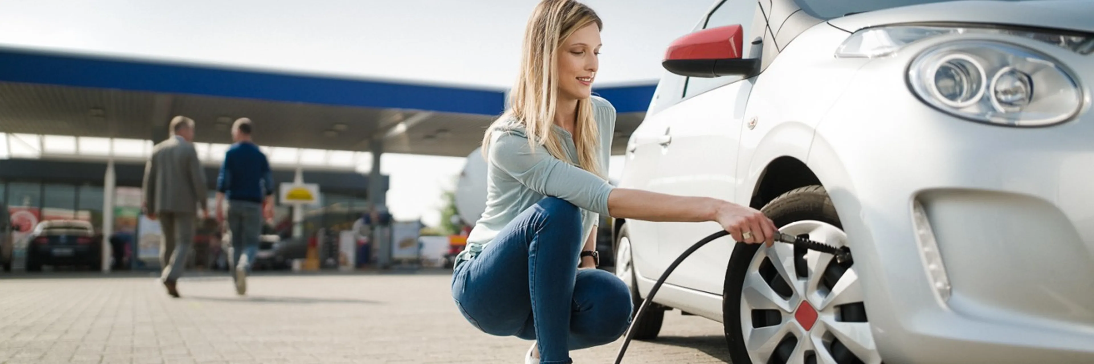 Vrouw die bij Q8 banden oppompt 