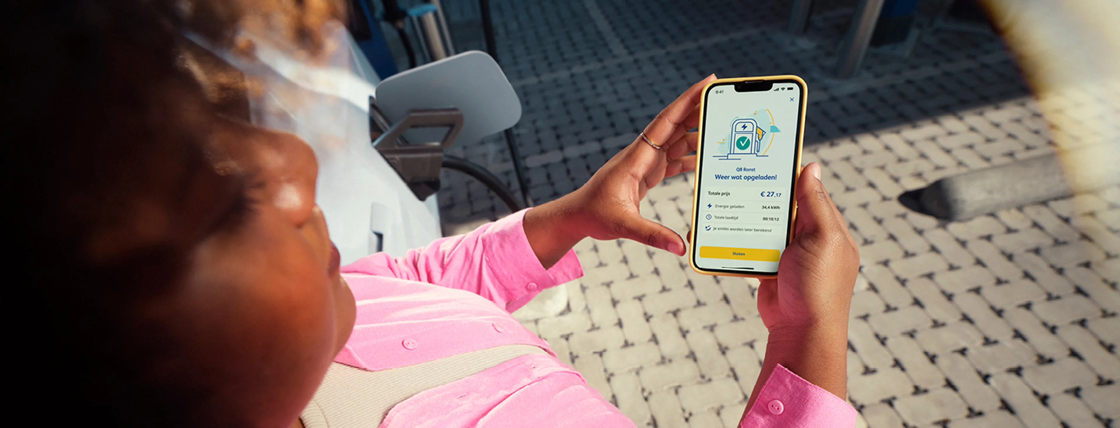 Personne consultant l’app Q8 pendant la recharge de sa voiture électrique à une borne Q8 electric.