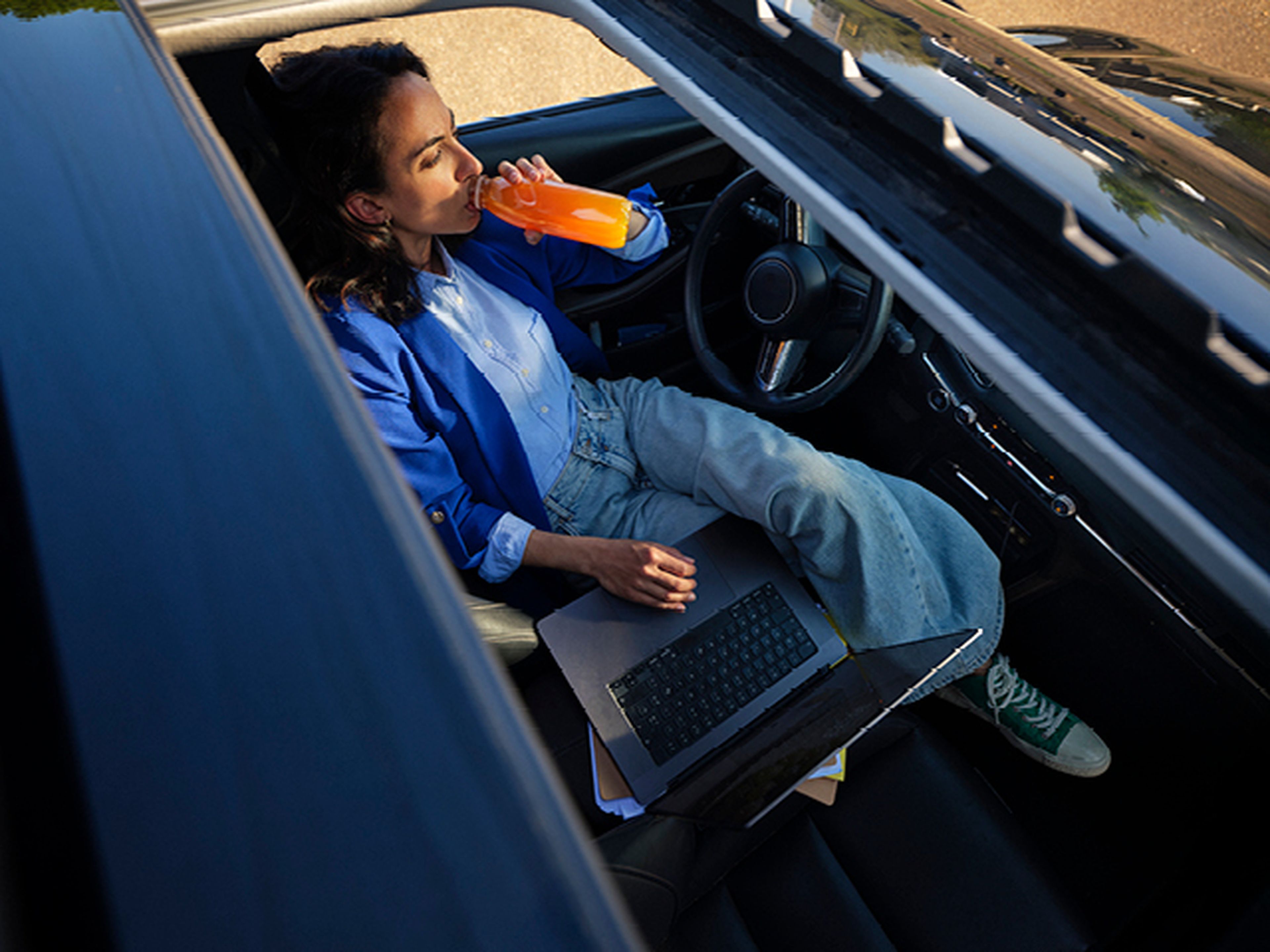 Femme travaille sur ordinateur portable en voiture chez Q8